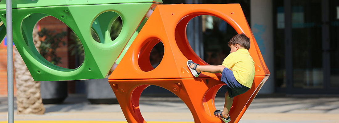 Boy climbing on a cube shaped climbing structure 